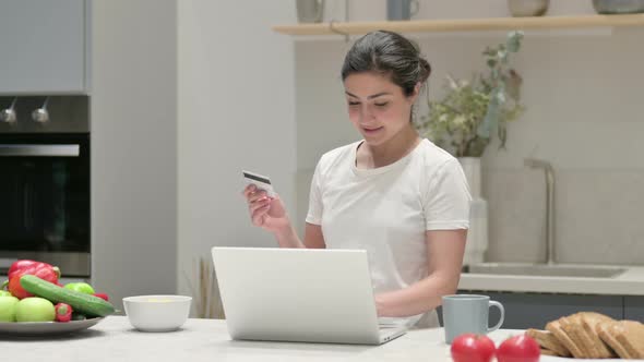 Indian Woman Making Online Payment on Laptop in Kitchen