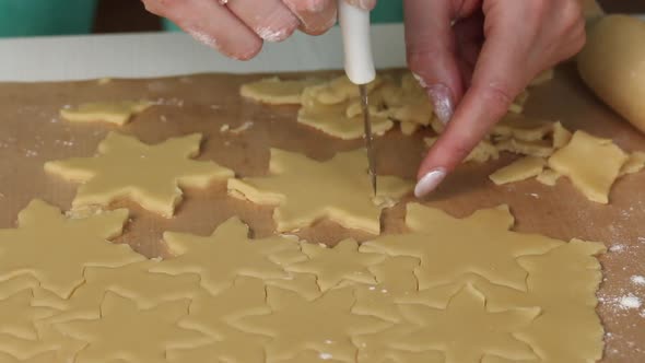 The Woman Cuts The Dough Into Pieces In The Form Of Snowflakes.