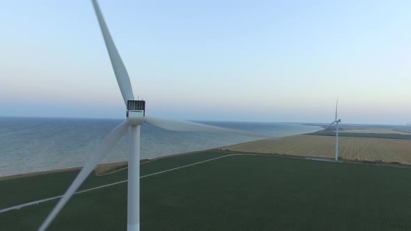 Windmills Along the Coast in Green Fields Under Blue Skies. Aerial Survey. Close Up