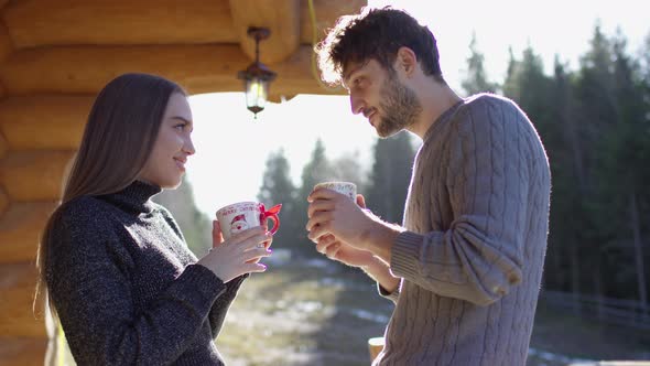 Young couple drinking from mugs and kissing