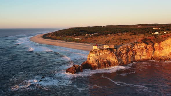 Nazare Portugal lighthouse near Praia do Norte during sunset, Aerial circle pan