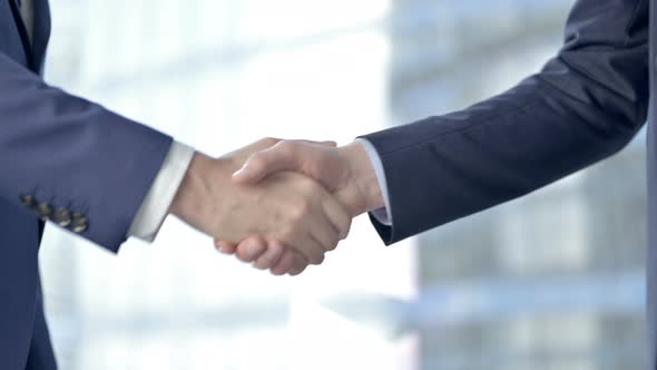 Close-up of Businessmen Shaking There Hands Against Boardroom Window