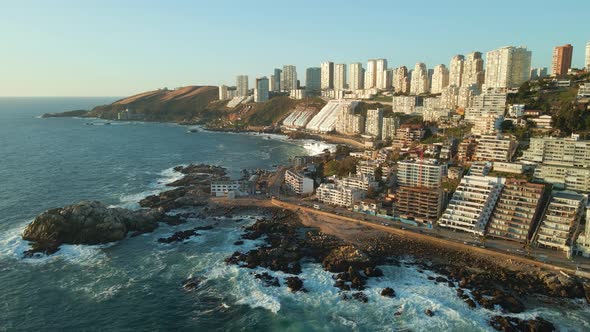 Aerial view orbiting scenic Reñaca  Avenida Borgoño tourism resorts cityscape with crashing ocean wa