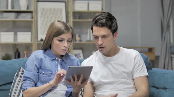 Astonished Couple in Shock While Using Tablet at Home