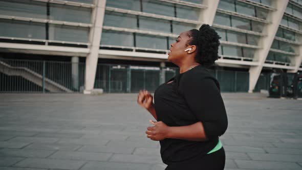 Overweight African American Woman Practicing Run Workout Outdoors Enjoying Music in Wireless