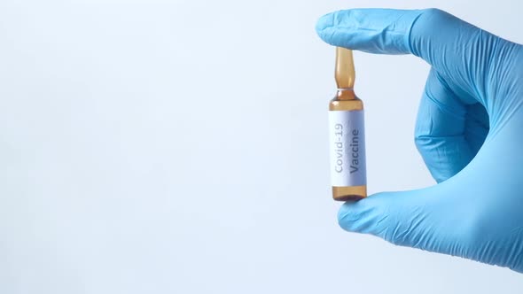 Hand in Latex Gloves Holding Glass Ampoule Vaccine with Copy Space