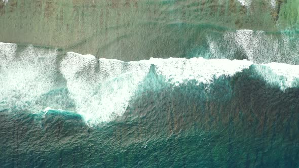 Big white waves crushing on shallow turquoise lagoon over sandy shore of tropical island, beautiful