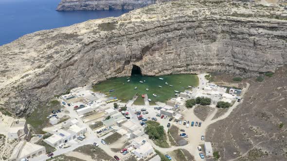 Ships sailing from town port,Dwerja cave in a rocky wall,Malta,aerial.