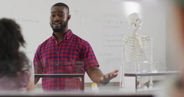Video of happy african american teacher with class of diverse pupils during anatomy lesson alt