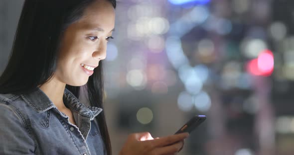 Woman use of mobile phone in city at night