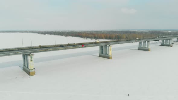 Cars Drive Along Long Bridge Over Frozen River on Sunny Day