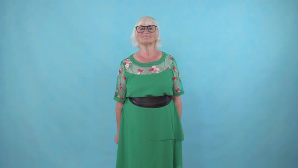 Elderly Woman Showing Disapproval with a Thumbs Down on a Blue Background