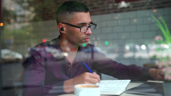 Hispanic male entrepreneur reading notes in cafe