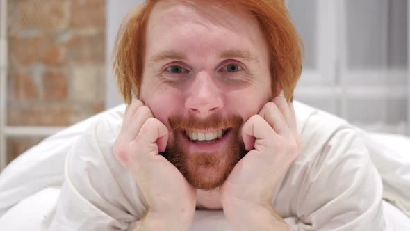 Close Up of Smiling Redhead Beard Man Face Lying in Bed