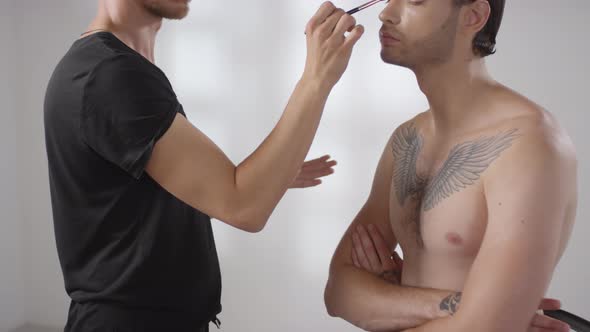 Make-Up Artist Putting Cosmetic Product on Eyelid of Man