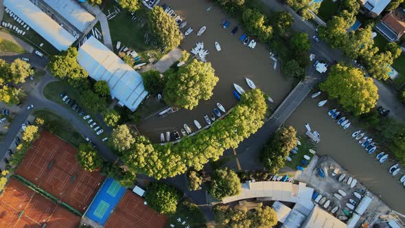 Aerial view of a nautical club with some tennis courts and boats docked. Jib up