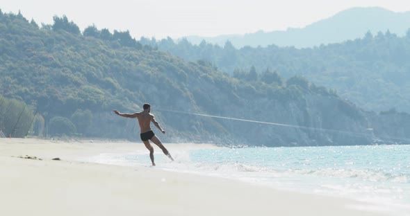 The Handsome Man with a Perfect Athletic Body in Swimming Trunks Having Fun on a Deserted Beach in