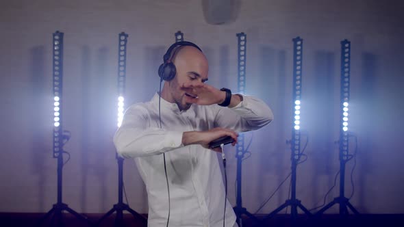 Live DJ Performance of Energetic Bald Man with Headphones Dancing on Party Concert Musician Stage