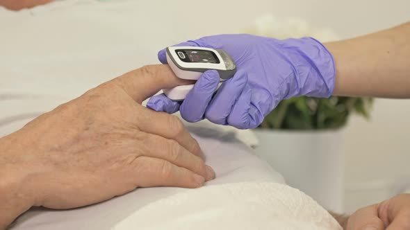 Doctor's Hands in Latex Gloves Measuring the Oxygen Level in the Blood of a Patient with Suspected