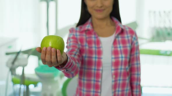 Friendly Girl Offering Apple in Dental Office, Healthy Teeth Concept, Vitamins