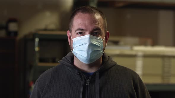 Male wearing face mask at work looking into camera