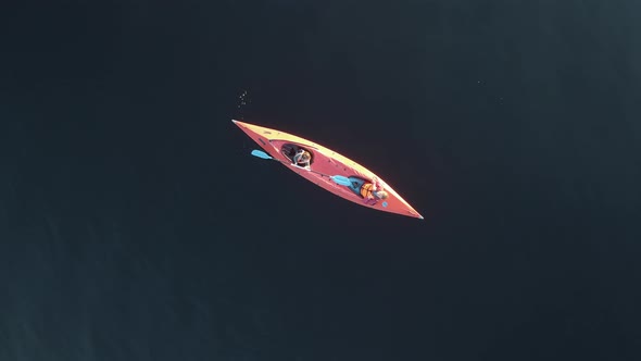 Girl with Child Sit in Red Kayak on Calm Lake, Drone Flies Up, Active Rest with Family Top View
