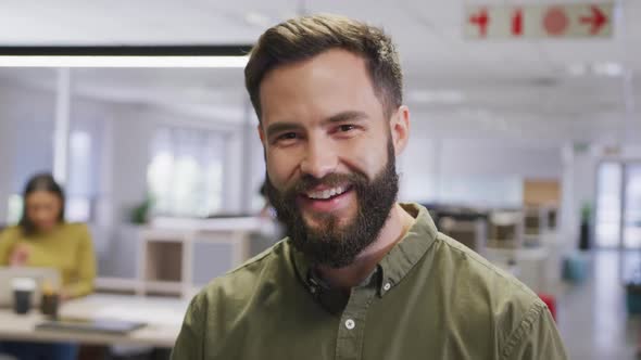 Portrait of happy caucasian businessman over business colleagues in office