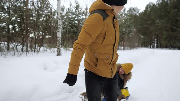 Man Is Pulling Tubing and Sliding His Wife and Child in the Snow. Winter Family Weekend.