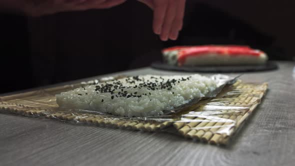 Chef's Hands Sprinkle Sesame Seeds on the Inside Out Sushi. Japanese Chef in