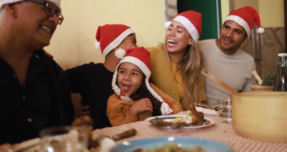 Happy latin family celebrating christmas and eating dinner together at home