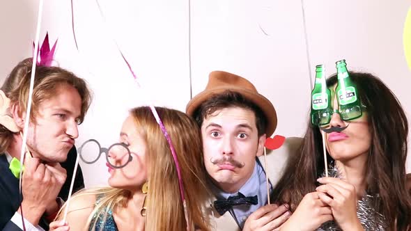 Funny couples playing with props in party photo booth