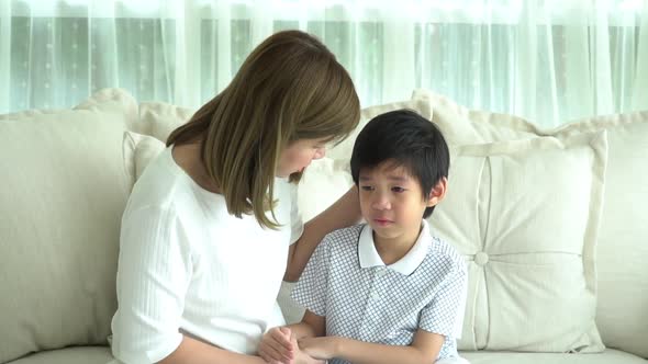 Asian Mother Embracing And Consoling Her Son