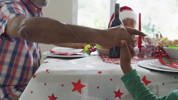 Happy african american multi generation family wearing santa hats and celebrating in kitchen