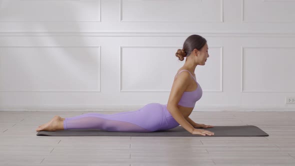 Wellness Attractive Asian woman in purple wear doing yoga Cobra pose