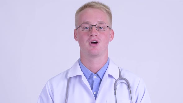 Face of Happy Young Blonde Man Doctor Talking To Camera