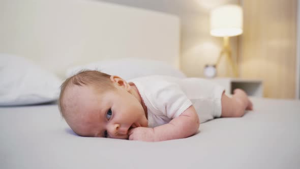 Newborn Baby Lying On Bed In Bedroom