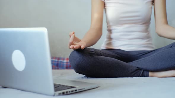 Young asian woman meditating in the lotus position on the bedroom