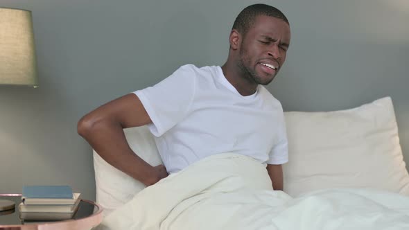 Exhausted Young African Man Having Back Pain in Bed 