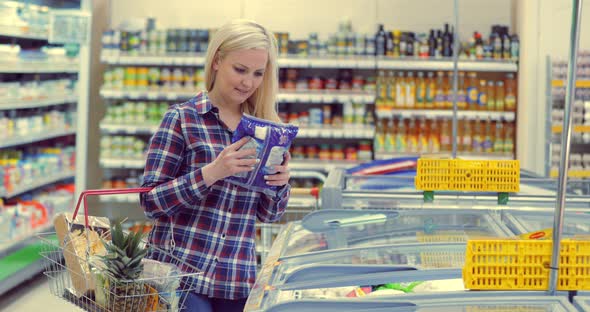 Woman Opening Glass Door of the Fridge and Taking Frozen Food at Supermarket