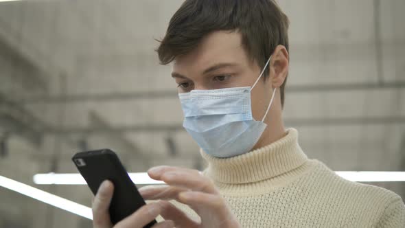 Man in Protective Mask Rubber Gloves Reading News on Smartphone Inside