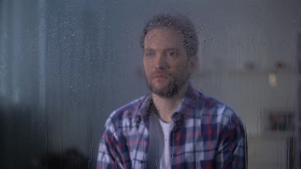 Lonely Sad Middle-Aged Man Looking Through Rainy Window, Bad Weather Conditions
