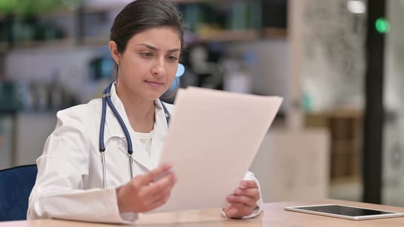 Focused Indian Female Doctor Doing Paperwork in Cafe 