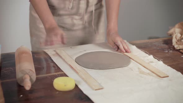 Artist Is Unrolling Clay on Table in Workshop, Using Pin, Close-up of Hands