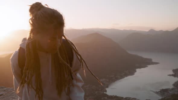 Camera follows hipster millennial young  Dreadlocks woman walking on mountain