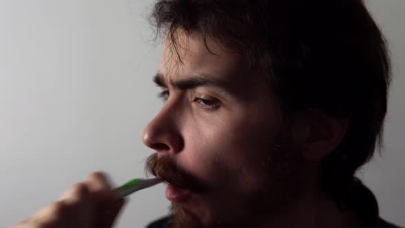 Closeup View of Bearded Tired Man Cleaning His Teeth By Brush and Toothpaste on White Background