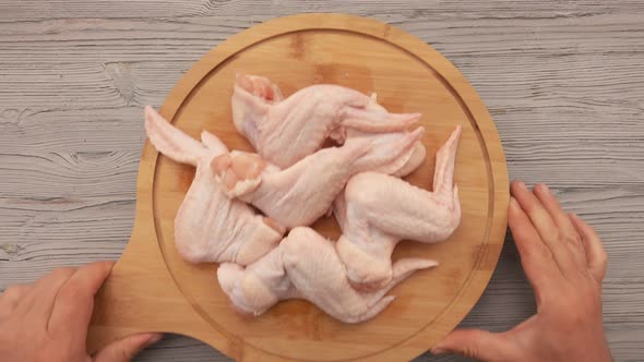 Top View of the Male Hands Placing Round Wooden Board Full of Chicken Wings