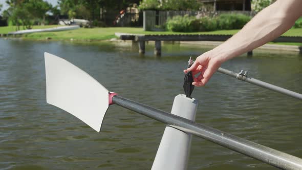 Male rower fixing the oar on the boat