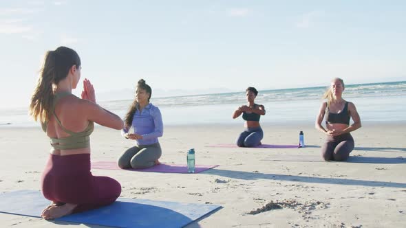 Group of diverse female friends meditating at the beach