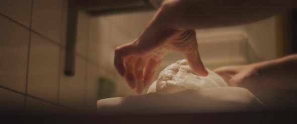 Chef slowly kneading traditional pizza dough in a restaurant kitchen. Close up, slow motion