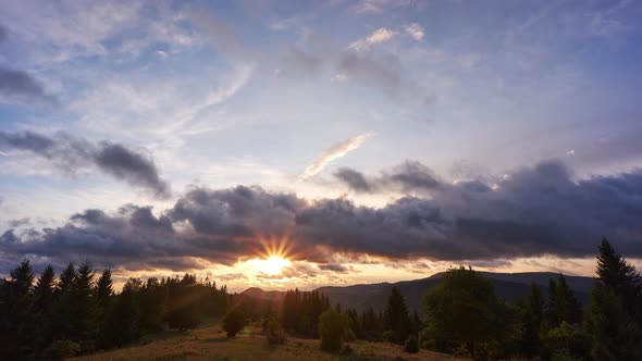 The clouds move quickly over the forest landscape at sunset alt